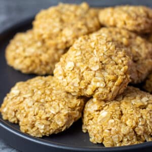 Square image of no bake pumpkin cookies on a black plate.