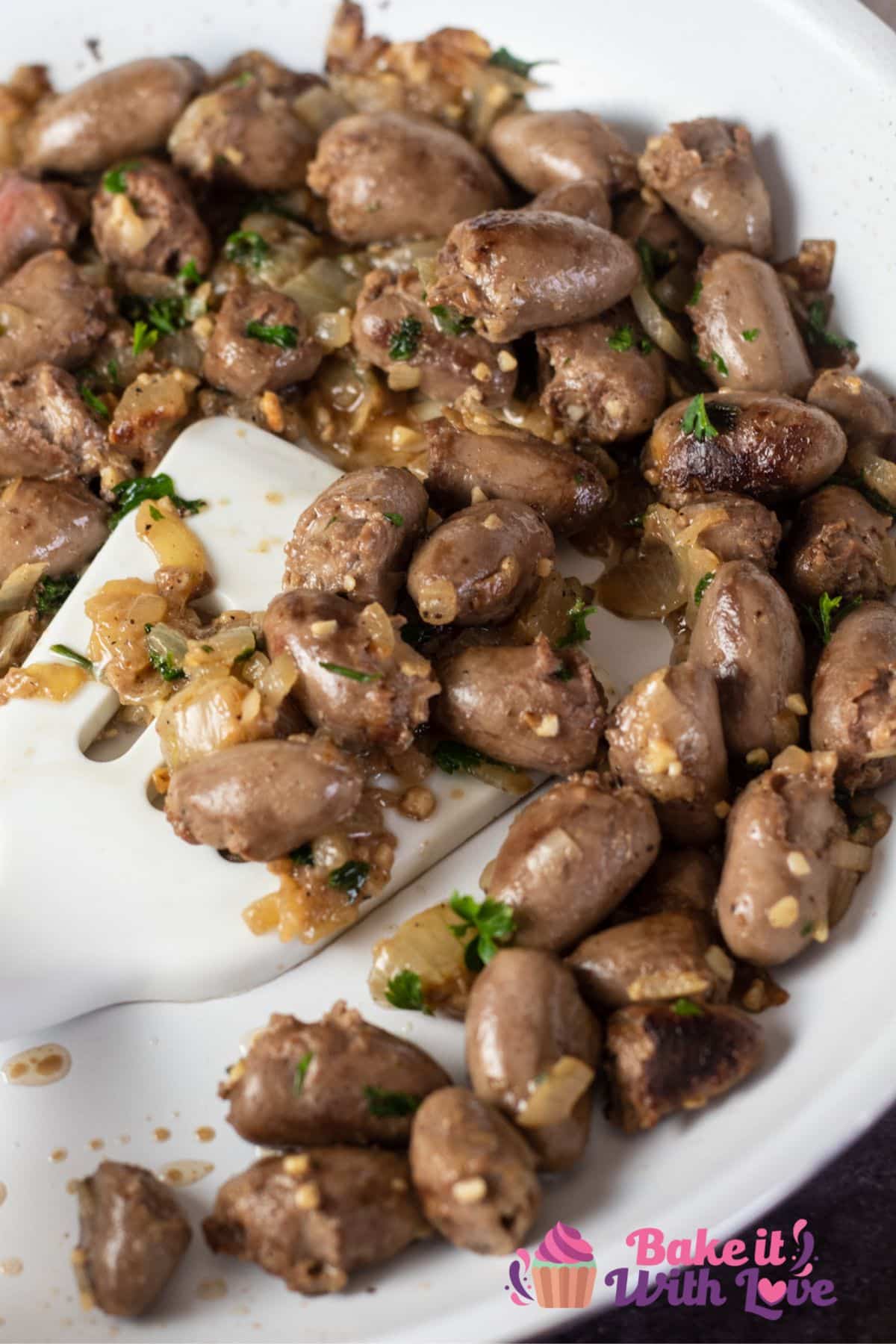 Tall image showing pan seared chicken hearts in a frying pan.