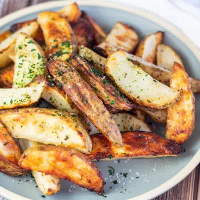 Square image of a plate of ranch roasted potato wedges.