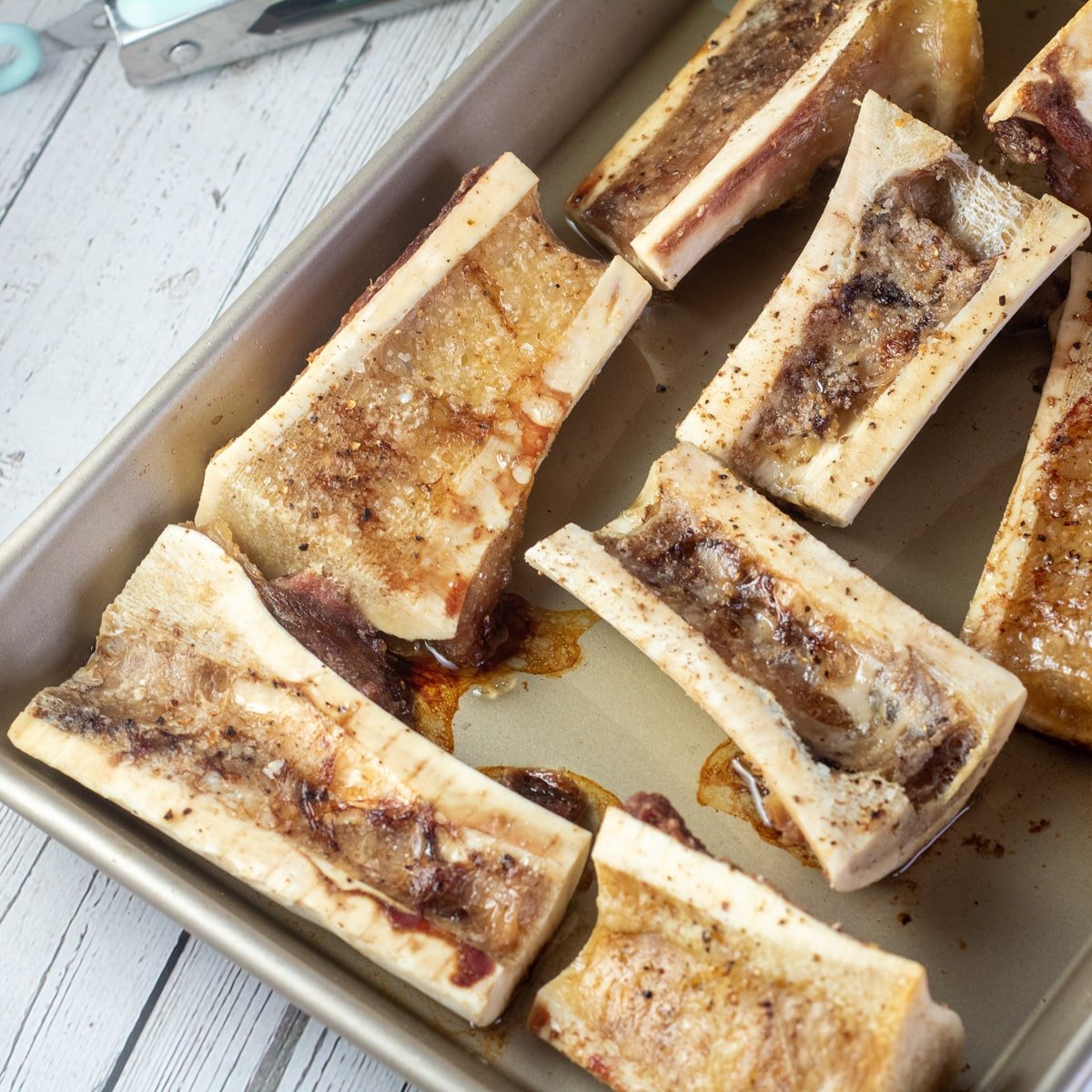 Square image of a tray with roasted beef bone marrow.