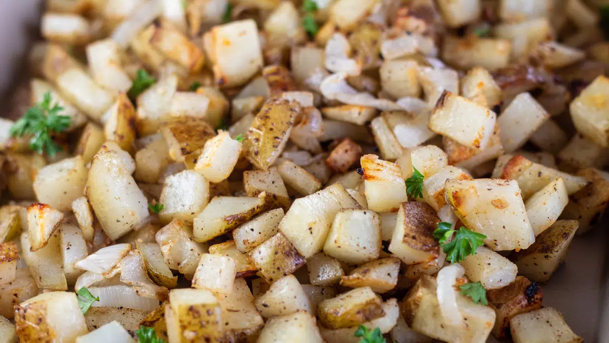 Wide image showing roasted potatoes and onions.