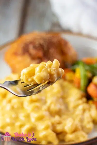 Tall image showing velveeta mac & cheese on a plate with chicken and veggies.