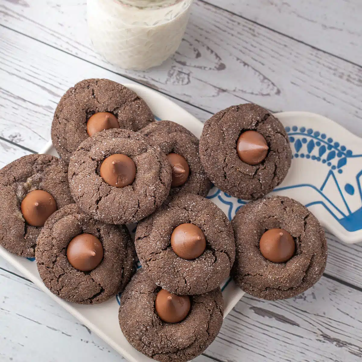 Best chocolate blossom cookies on serving plate with a quilted jar filled with milk.