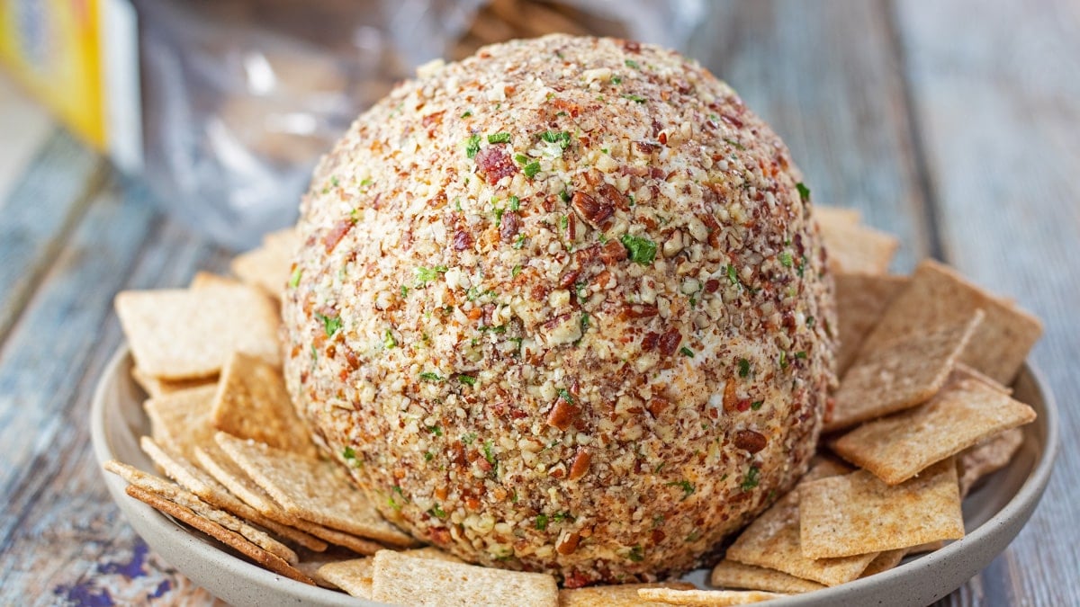 Wide closeup on the best ranch cheese ball with cheddar, mozzarella, bacon, and chives plus crushed pecan crust coating.