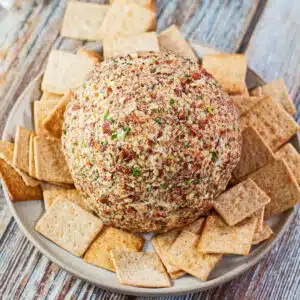 Ranch cheese ball in shallow plate served with wheat thin crackers.