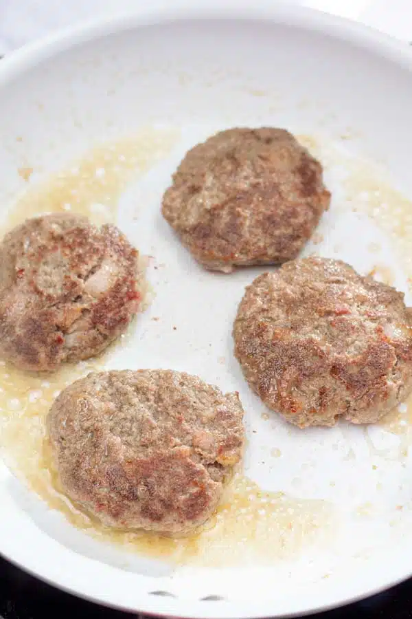 Process image 5 showing sausage patties browned and turned over in frying pan.