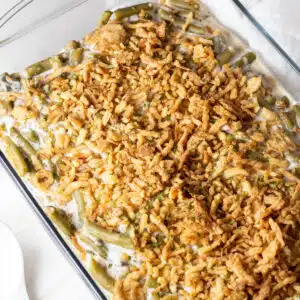 Close up square image of Campbell's green bean casserole in a glass baking dish.