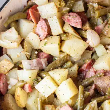 Wide image of green bean potato and sausage casserole in baking dish.