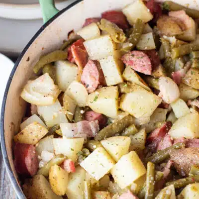 Square image of green bean potato and sausage casserole in baking dish.