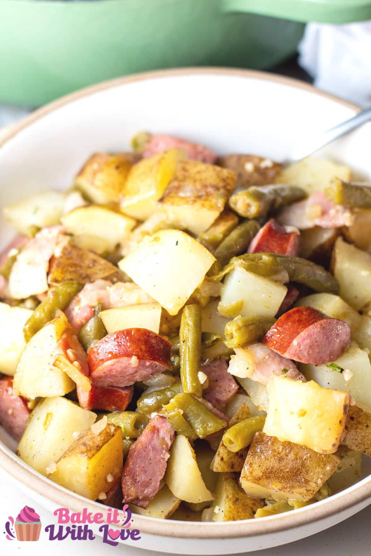 Tall image of green bean potato and sausage casserole in white bowl.