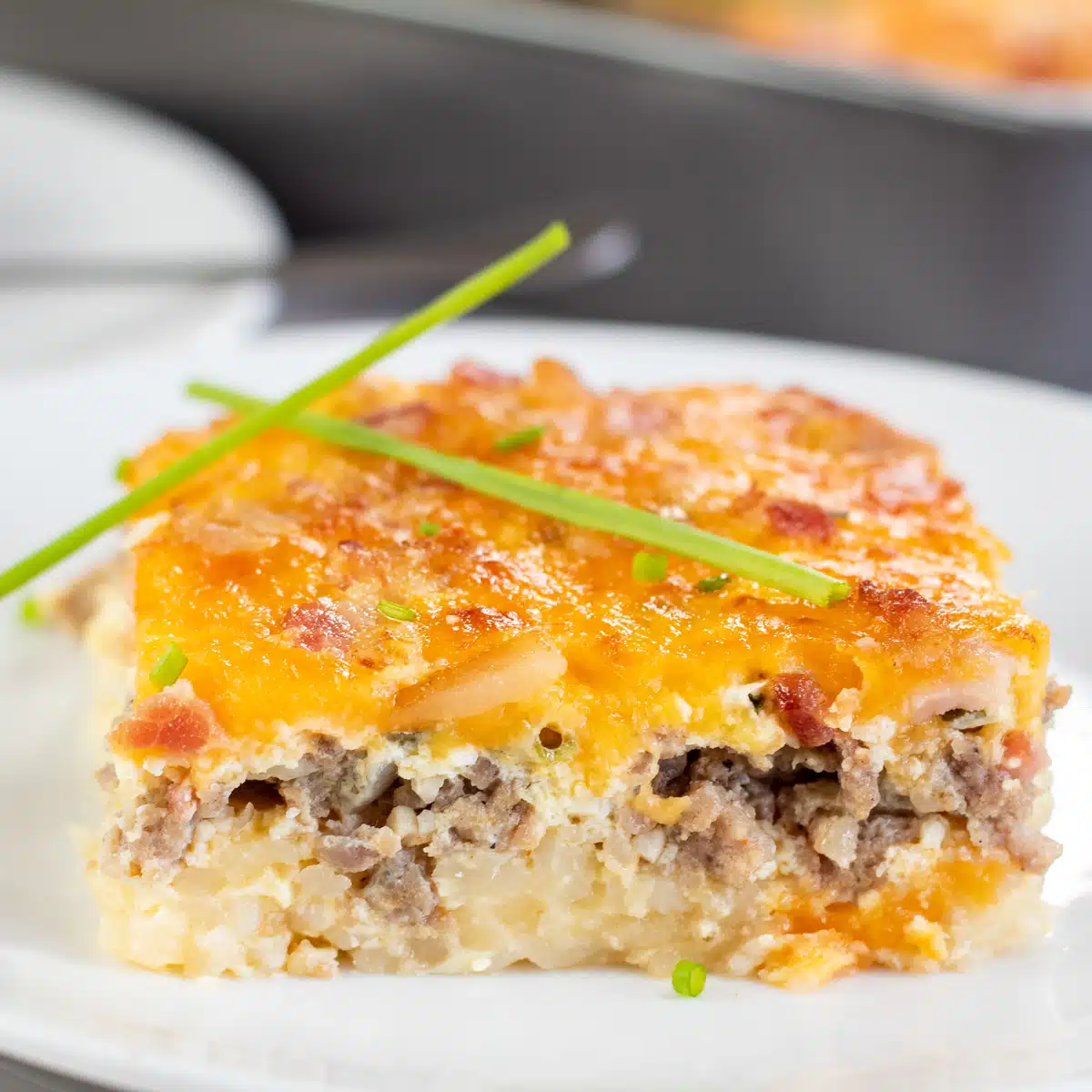Square image of a slice of this hashbrown sausage bacon egg casserole.
