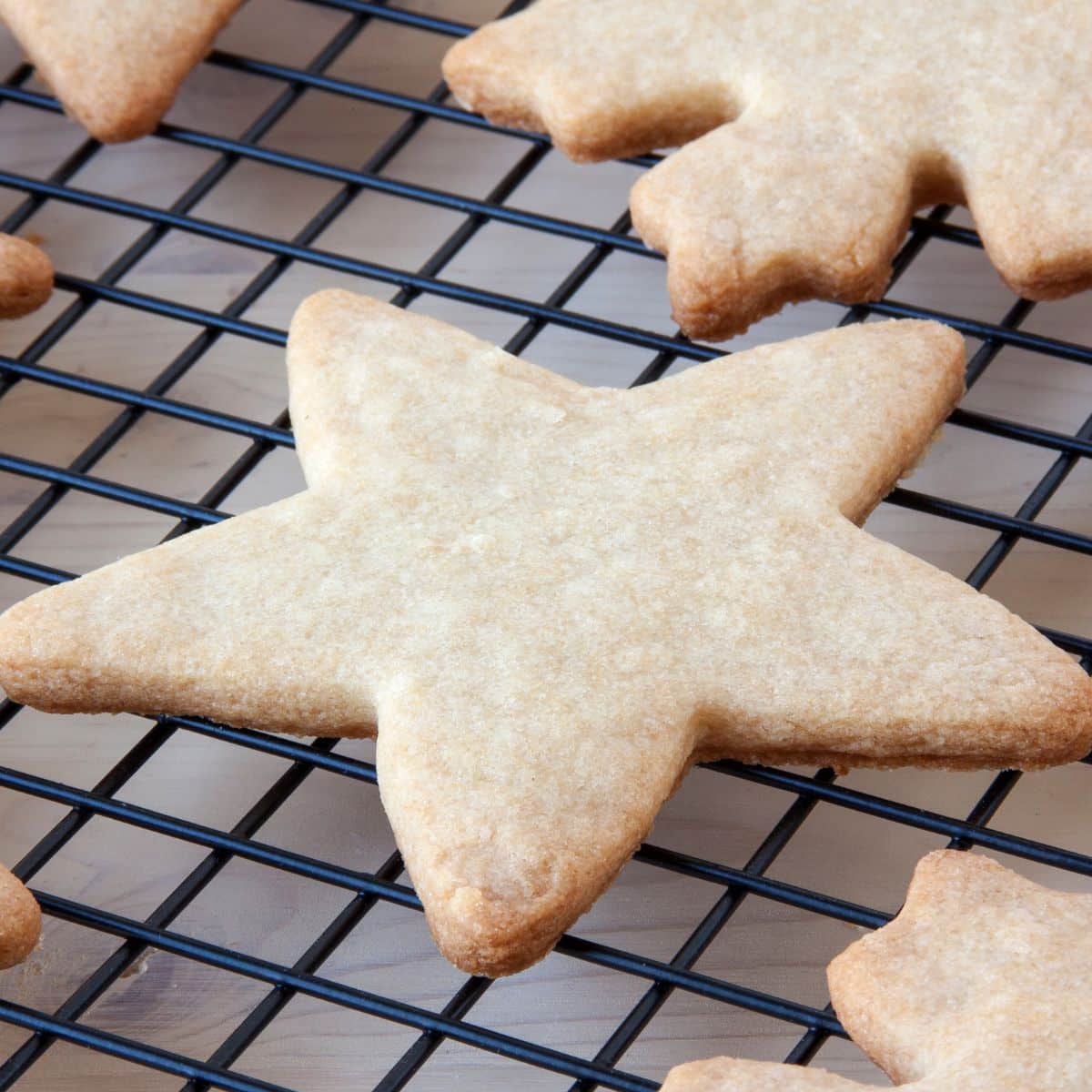 Square image of baked star shaped sugar cookies on a cooling rack.