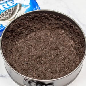 Square image of oreo cookie crust in a springform pan.