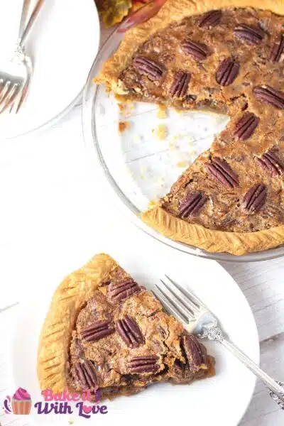 Tall image of pecan pie with a slice on a plate on a white background.
