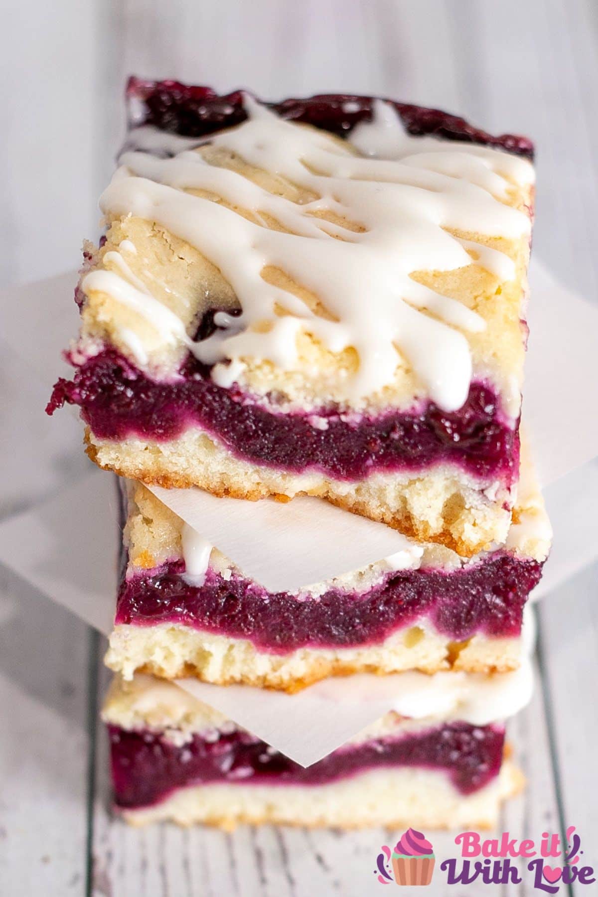 Best blueberry pie bars recipe with creamy icing, sliced and stacked on light background.
