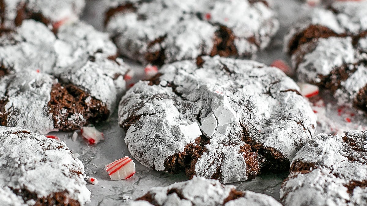 Closeup on the baked chocolate peppermint crinkle cookies with some crushed candy canes sprinkled around them.