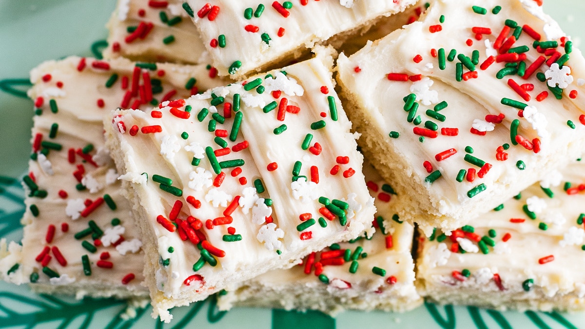 Best Christmas sugar cookie bars to bake for the holiday season, stacked on a festive tree shaped serving platter.