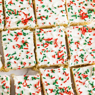 Les meilleures barres de biscuits au sucre de Noël à trancher et à servir avec des saupoudres festives sur un délicieux glaçage à la crème au beurre à la vanille.