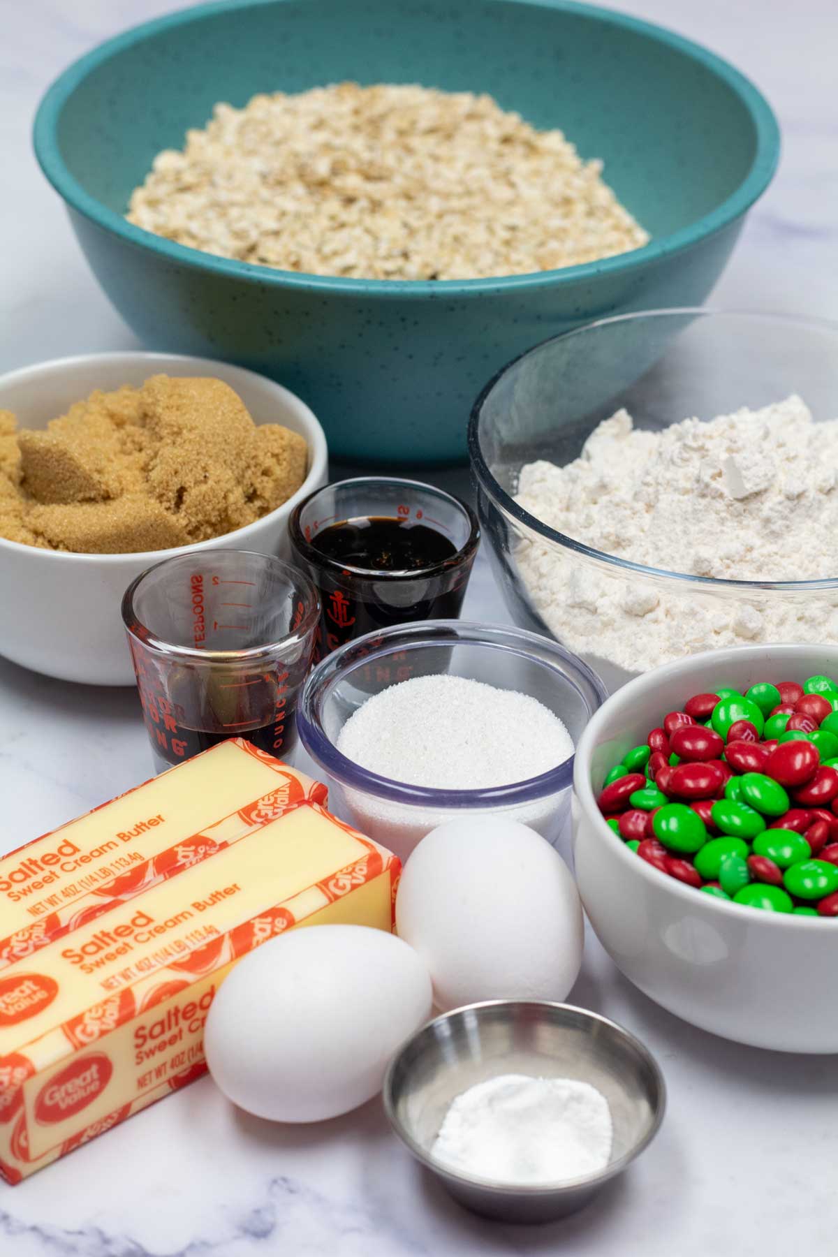 Tall image showing ingredients needed for Christmas M&M oatmeal cookies.