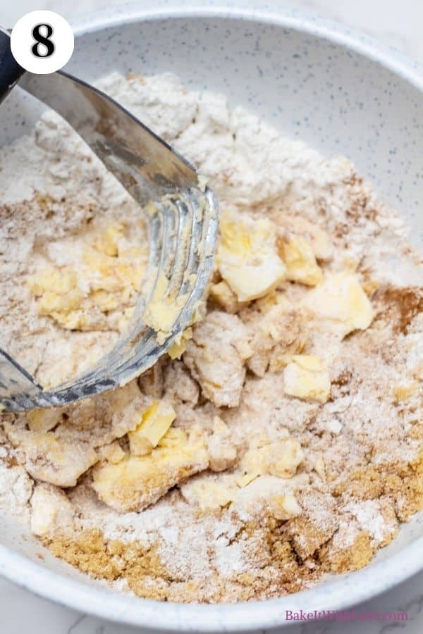 Dutch apple pie process photo 8 showing a pastry cutter being used to combine the streusel ingredients in a mixing bowl.