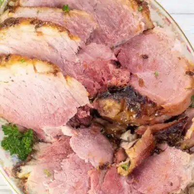 Square image of sliced gingersnap crusted ham on a serving platter.