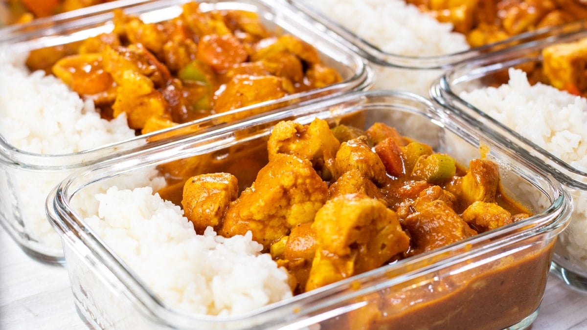 Широко изображение на приготвено за хранене пиле с масло в отделни стъклени съдове с ориз.