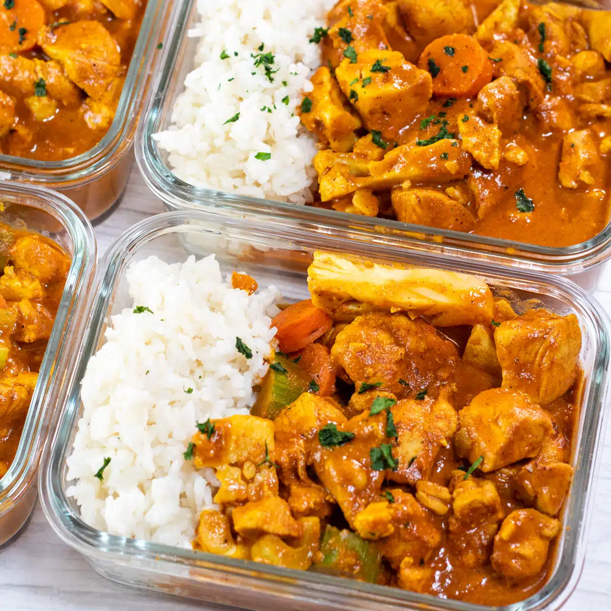 Square image of meal prep butter chicken in individual glass containers with rice.
