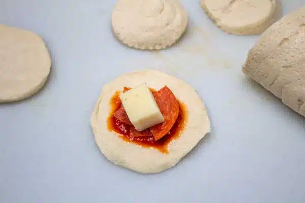 Process image 2 showing dough with sauce, pepperoni, and cheese.