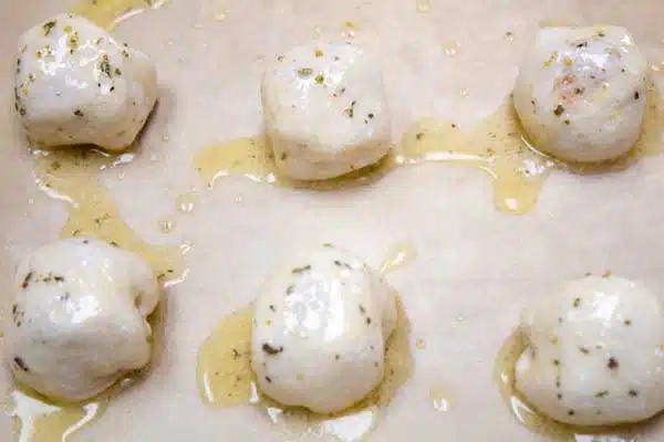 Process image 5 showing melted butter and herbs brushed over pastry balls.