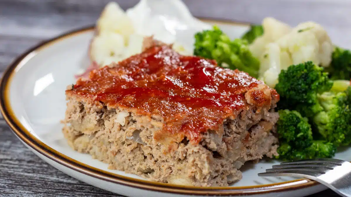 Wide image of a slice of turkey meatloaf on a white plate.