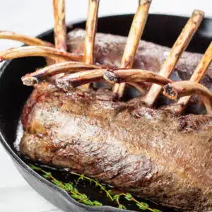 Square image of venison rib roast in a cast iron pan.