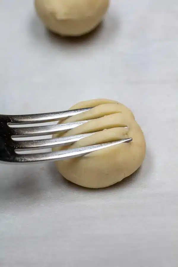 Process image 9 showing using a fork to make indentations in the cookie balls.