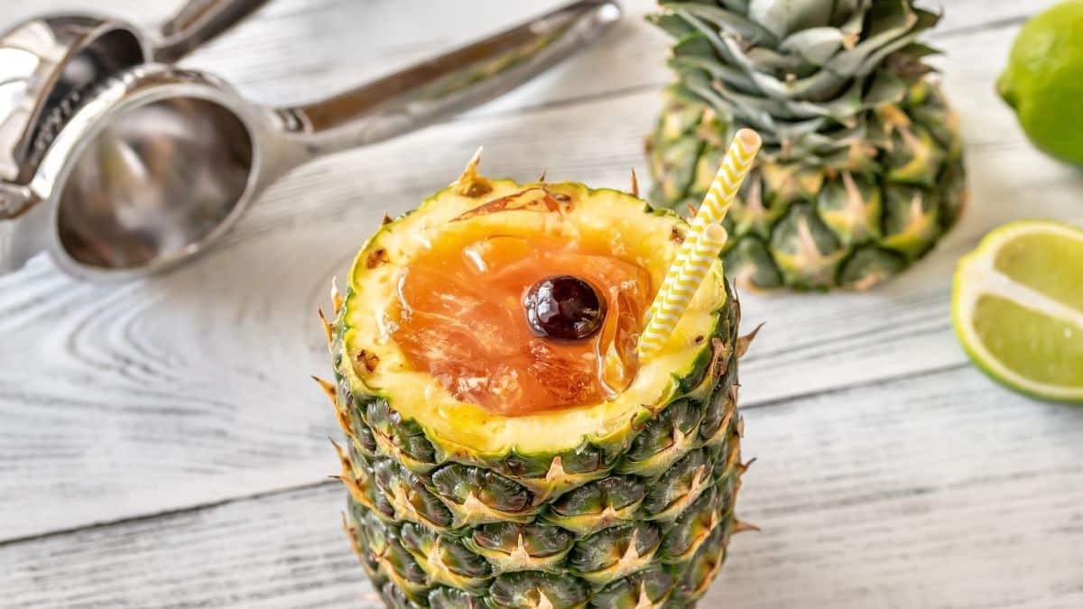 Wide image of a Bahama Mama cocktail in a cut open pineapple.