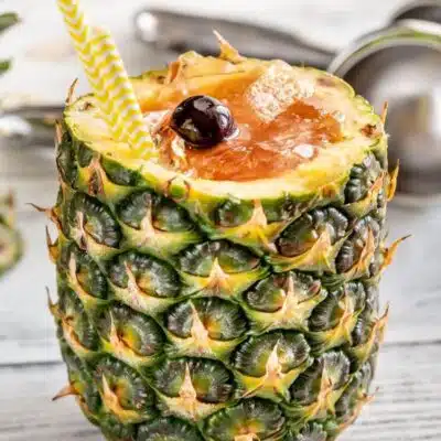 Square image of a Bahama Mama cocktail in a cut open pineapple.