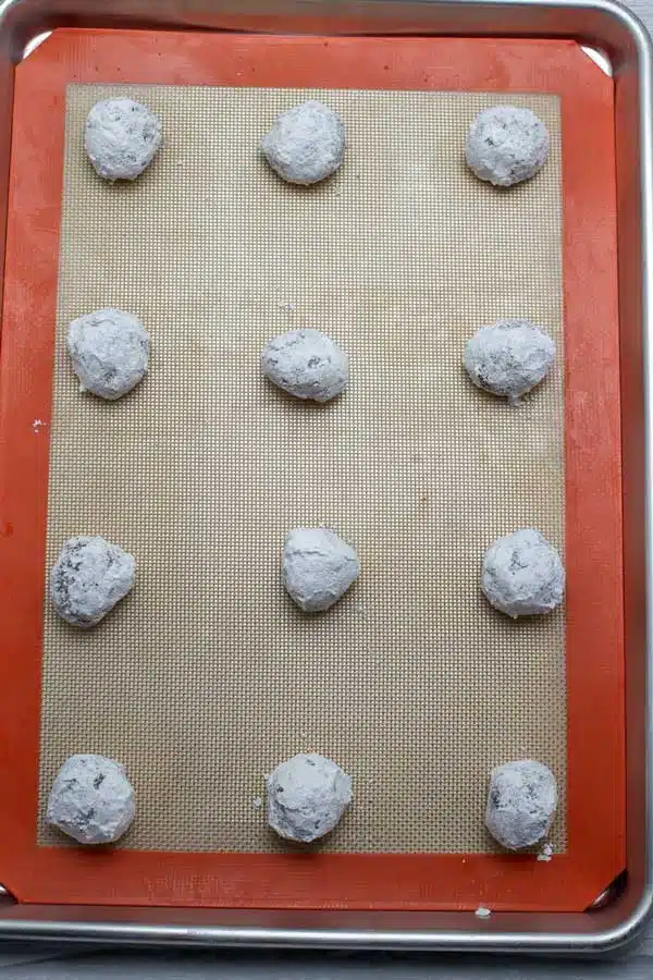 Chocolate crinkle cookies process photo 10 arranged on baking sheet with silpat mat.