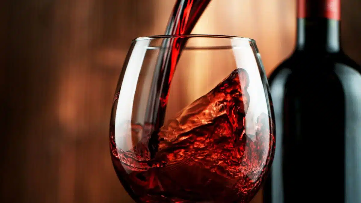 Red wine being poured in a glass to enjoy as you use the rest of the bottle for cooking up a tasty meal.