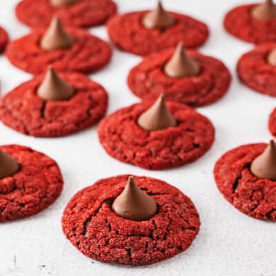Best red velvet blossom cookies with red sanding sugar and topped with Hershey's Kisses chocolate candies.