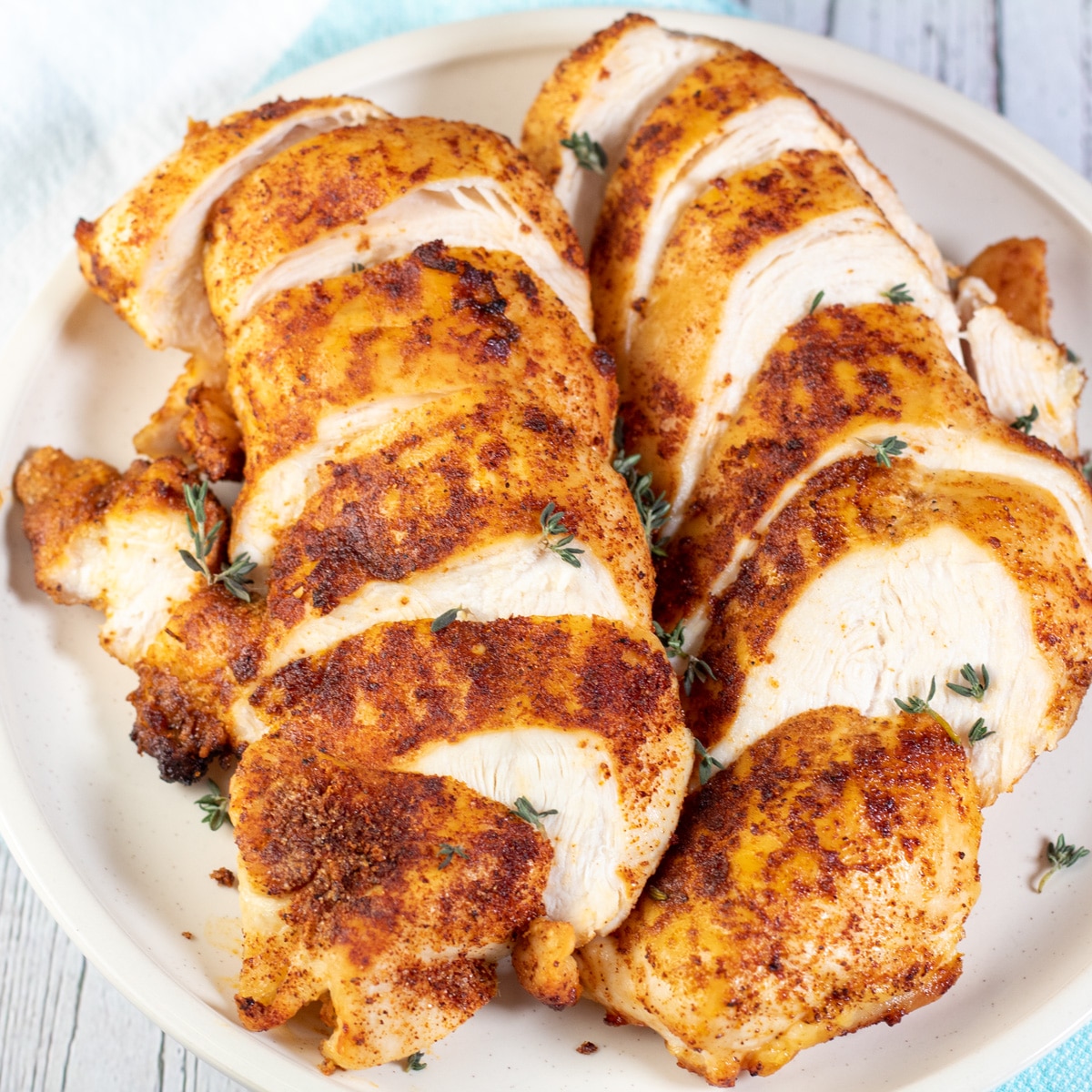 Square image showing sliced boneless skinless air fryer chicken breasts.