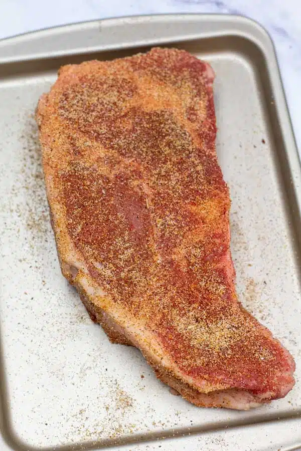 Process image 2 showing seasoning the NY strip steak.