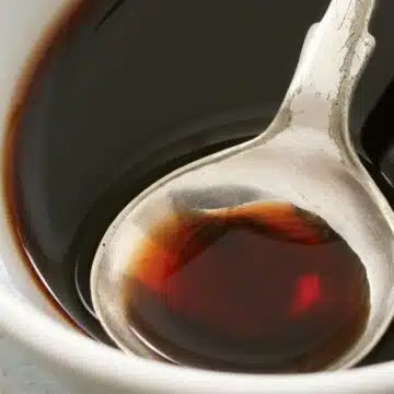 Wide image showing balsamic reduction in a small white bowl.