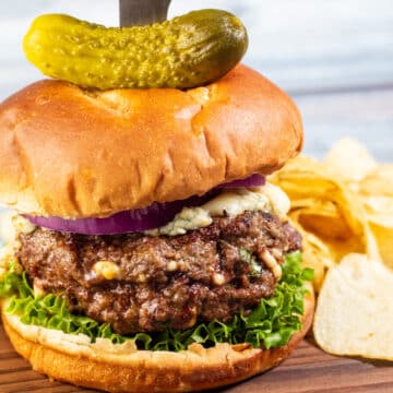 Ampla imagem de hambúrguer de queijo azul em uma tábua.
