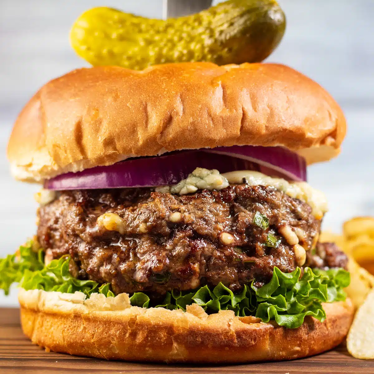 Image carrée de burger au fromage bleu sur une planche à découper.