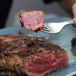Square image of blue rare steak.