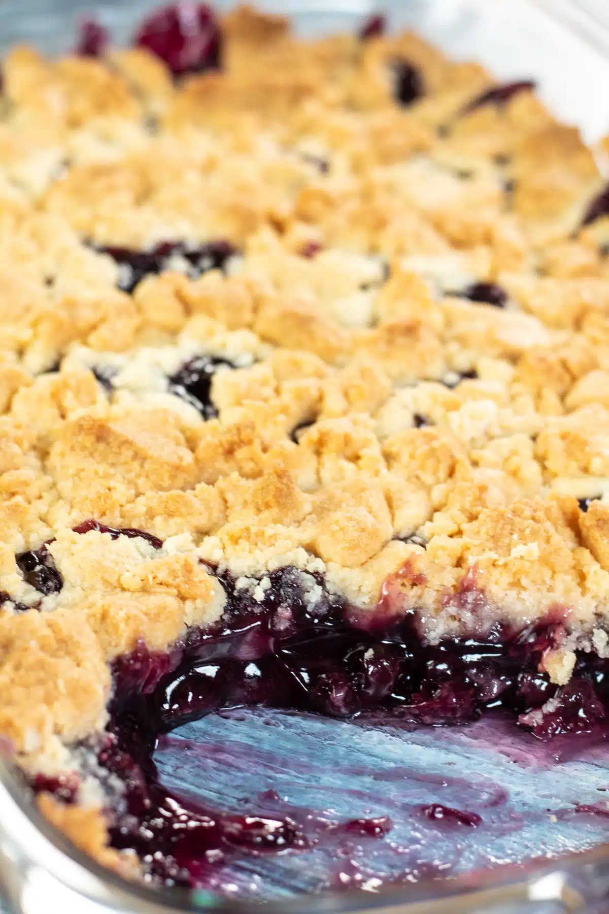 Tall image of blueberry dump cake in glass baking dish.