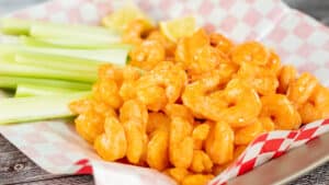 Wide image showing buffalo shrimp in a basket with celery.