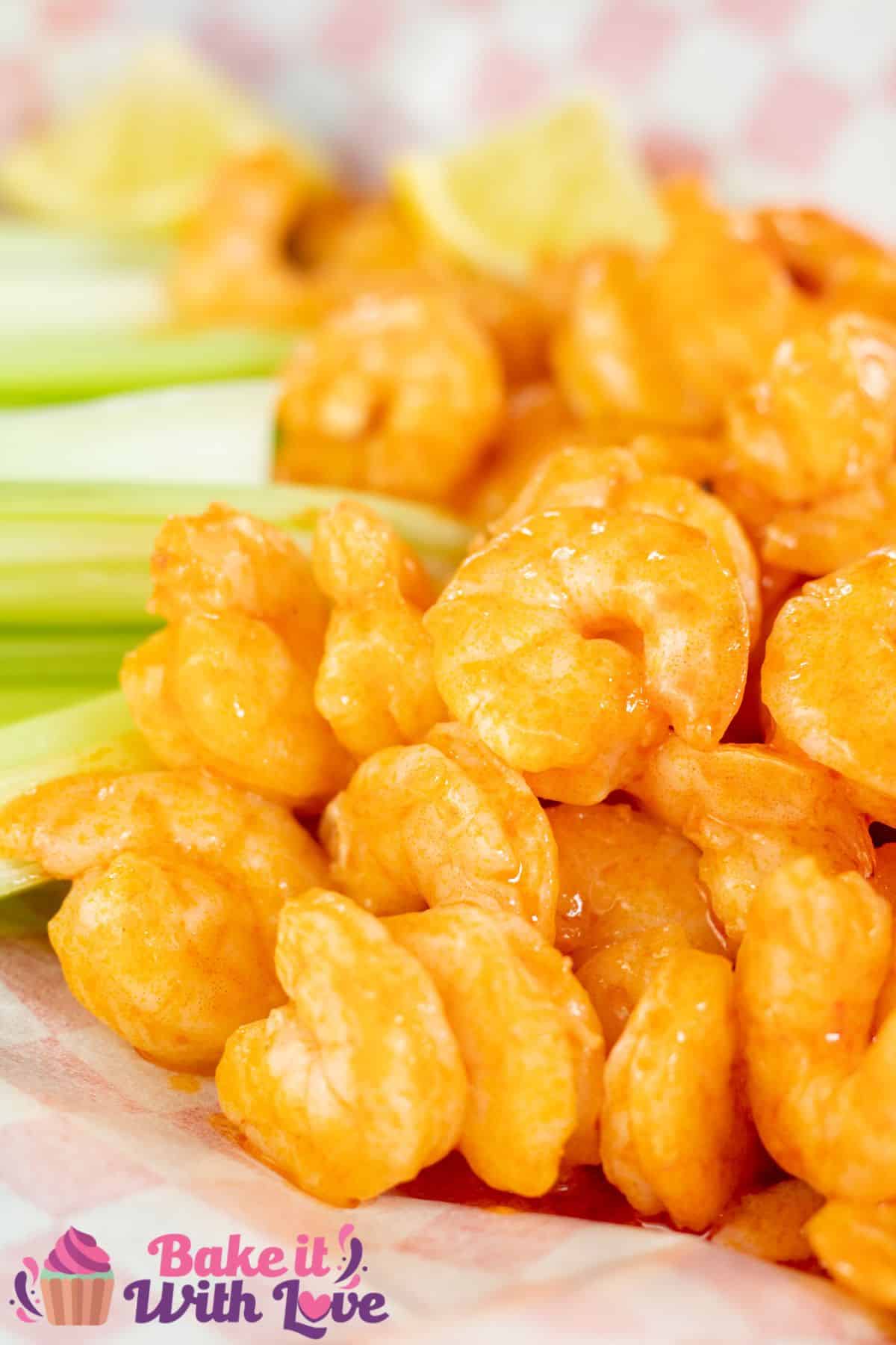 Tall image showing buffalo shrimp in a basket with celery.