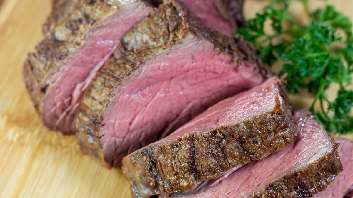 Wide image of sliced chateaubriand on a cutting board.