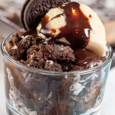 Square image of Oreo dump cake in a glass dish with ice cream.