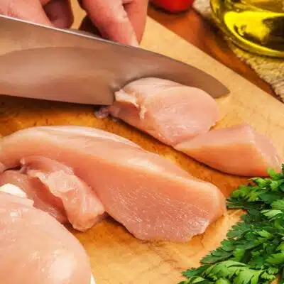 Pin image showing slicing raw chicken breast.