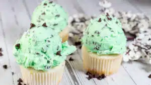 Wide image showing mint chocolate chip buttercream frosting on a cupcake.
